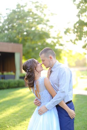 Young caucasian fiancee kissing groom in park. Concept of wedding and love.の写真素材