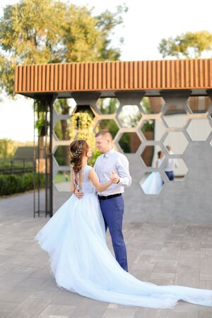 Caucasian bride in white dress and groom dancing outside. Concept of wedding photo session outdoor.の写真素材