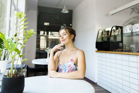 Young beautiful woman sitting at cafe near window. Concept of photo session at restaurant.の写真素材
