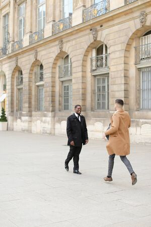 Caucasian man running meet afroamerican male person near building. Concept of happy gays and meeting.の写真素材