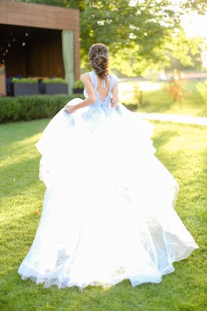Back view of fiancee walking in park and wearing white dress. Concept of wedding and bridal photo session.の写真素材