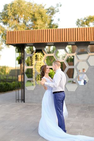 Caucasian bride and groom dancing outside in yard. Concept of wedding photo session outdoor.の写真素材