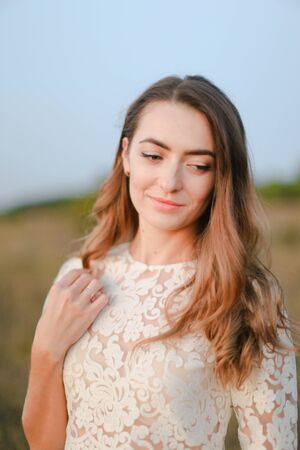 Portrait of caucasian happy fiancee standing in steppe and wearing white dress. Concept of nature, bridal photo session on nature and beauty.の写真素材