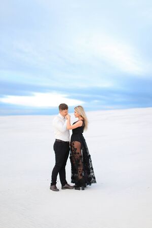 Young boy in white shirt hugging woman wearing black dress in winter steppe. Concept of winter photo session, relationship and love, happy couple.の写真素材