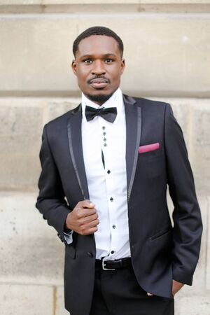 Afro american happy man wearing suit and standing near wall outside. Concept of black businessman.の写真素材