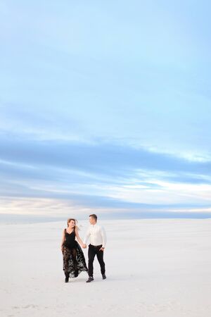 Young blonde girl in black transparent dress walking in winter steppe. Concept of seasonal photo session and love.の写真素材