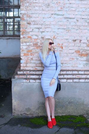 Woman blond hair slim athletic figure near brick wall stands wearing sunglasses.の写真素材