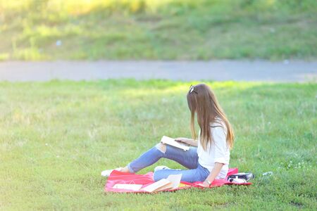feminine working outdoors with papers in glasses. in the park for a laptop fast food snack and uses a tabletの写真素材