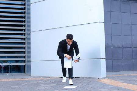 Arabic businessman handsome masculine guy drops and collects important papers or documents.の写真素材