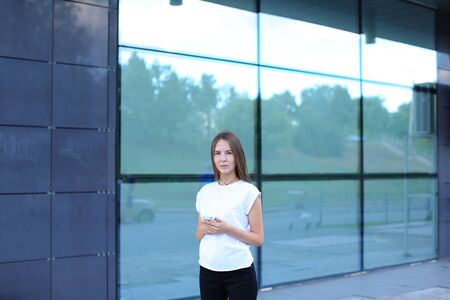Young beautiful business woman entrepreneur with long hair wearing a suit standing near center business technology. Female work, negotiating, solves problems, dials, talking on smart phoneの写真素材