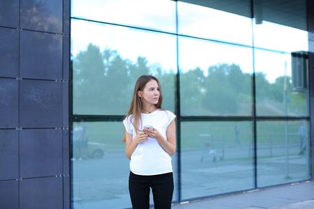 Young beautiful business woman entrepreneur with long hair wearing a suit standing near center business technology. Female work, negotiating, solves problems, dials, talking on smart phoneの写真素材
