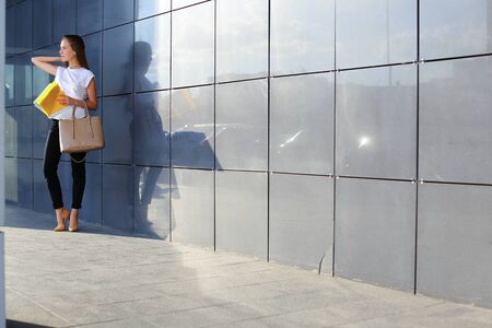 Female work, negotiating, solves problems, walking to camera holds document talking on smart phone indignant displeased. Young beautiful business woman entrepreneur with long hair wearing suit standing near center technology.の写真素材