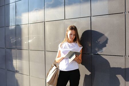 Female work, negotiating, solves problems, browsing touch looking tablet. Young beautiful business woman entrepreneur with long hair wearing suit standing near center technology sun.の写真素材