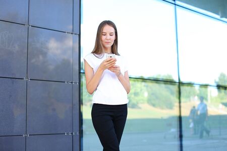 Young beautiful business woman entrepreneur with long hair wearing a suit standing near center business technology. Female work, negotiating, solves problems, dials, talking on smart phoneの写真素材