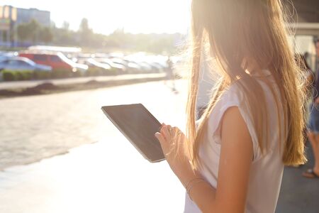 Female work, negotiating, solves problems, browsing touch looking tablet. Young beautiful business woman entrepreneur with long hair wearing suit standing near center technology sun.の写真素材