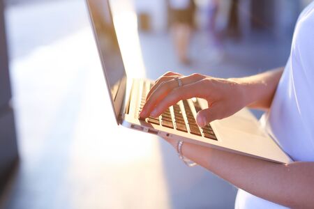 Hand lady press tauchpad keyboard on laptop. Young beautiful female business woman entrepreneur long hair wearing suit standing near center technology sunの写真素材