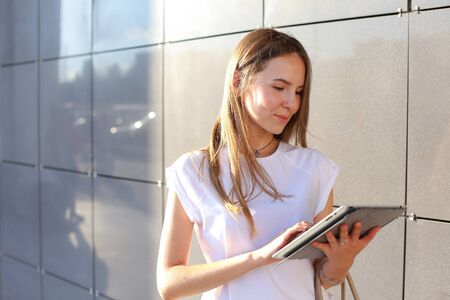 Female work, negotiating, solves problems, browsing touch looking tablet. Young beautiful business woman entrepreneur with long hair wearing suit standing near center technology sun.の写真素材