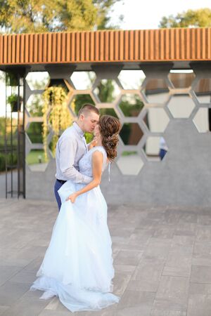 Caucasian bride and groom kissing and dancing outside. Concept of wedding photo session outdoor.の写真素材