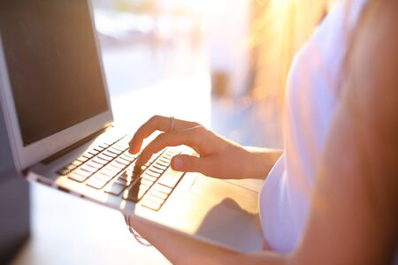 Hand lady press tauchpad keyboard on laptop. Young beautiful female business woman entrepreneur long hair wearing suit standing near center technology sunの写真素材