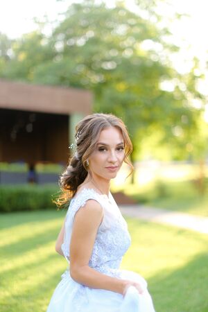 European pretty fiancee standing in park. oncapt of bridal hair do and wedding photo session on nature.の写真素材