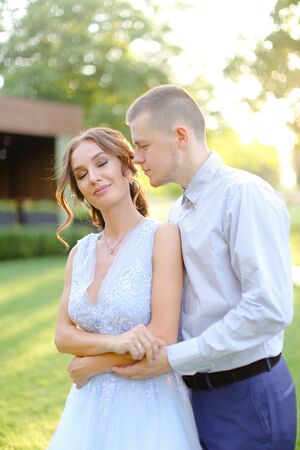 Handsome groom kissing bride outside in garden. Concept of love, wedding and happy couple.の写真素材