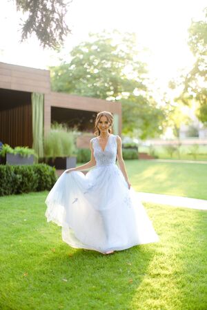 Caucasian young fiancee walking in park, sun rays. on green grass. Concept of bridal photo session andの写真素材
