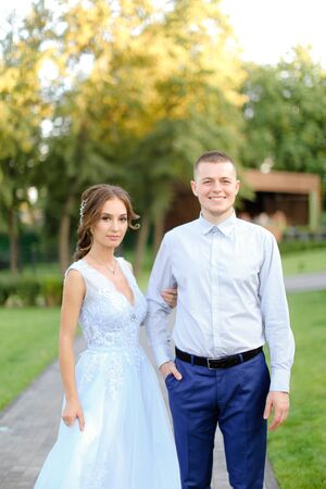 Young fiancee standing with caucasian groom in park. Concept of happy couple and wedding photo session outside.の写真素材