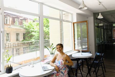 Young caucasian happy woman showing thumbs up and sitting with laptop at cafe. Concept of social networks and fast internet.の写真素材
