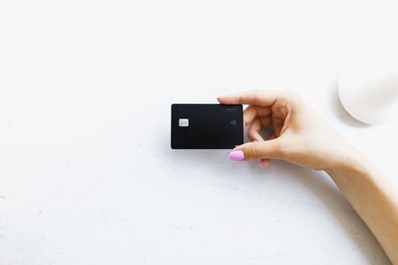 Female hand keeping black debit card in white background. Concept of bank account and credit.の写真素材