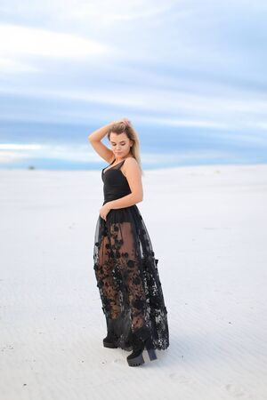 Young pretty woman wearing black transparent dress and walking on snow. Concept of vogu and seasonal photo session.の写真素材