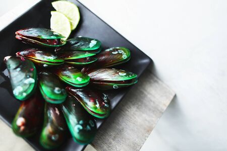 Tasty mussels on black square plate in white background. Concept of healthy seafood and restaurant menu in Thailand.の写真素材