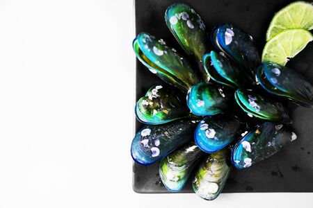 Tasty dark mussels and sliced lime on black square plate with lime in white background. Concept of healthy seafood and restaurant menu in Thailand.の写真素材