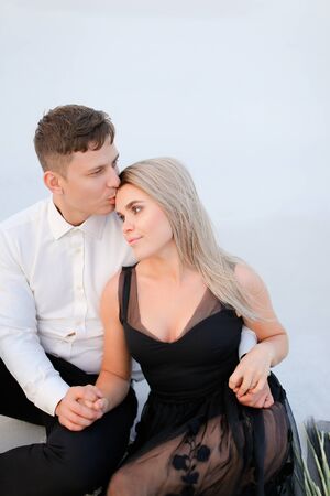 Young man hugging and kissing woman wearing black dress in white background. Concept of love and relationship.の写真素材