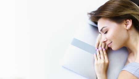 Banner of blonde female freelancer lying on laptop in white background with copy space. Concept of having break and preparing before exam.の写真素材