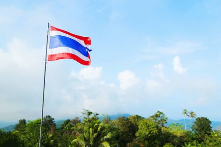 flag of Thailand against blue sky, beautiful green nature and mountains, blue white and red colours. photo taken from the statue of the Big Buddhaの写真素材