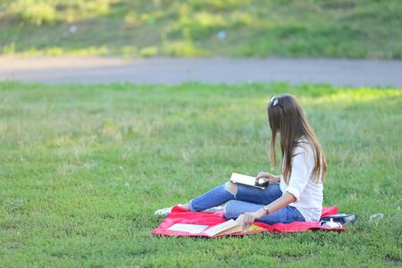 feminine working outdoors with papers in glasses. in the park for a laptop fast food snack and uses a tabletの写真素材