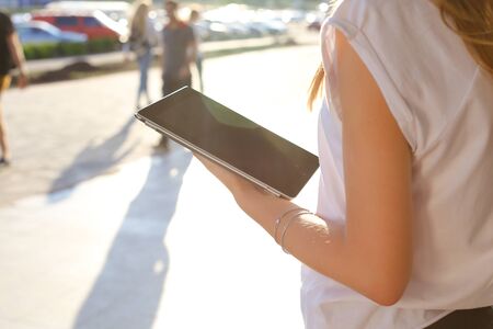 Female work, negotiating, solves problems, browsing touch looking tablet. Young beautiful business woman entrepreneur with long hair wearing suit standing near center technology sun.の写真素材