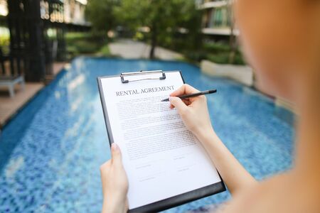 Close-up of girl's hand sign document. concept of renting an apartment or car In travel, new contract is an arrangement. Front used with Open Font Licenseの写真素材