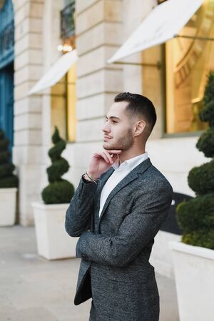 Young cacuasian male person wearing suit standing near building outdoors. Concept of fashion and businessman, urban life.の写真素材