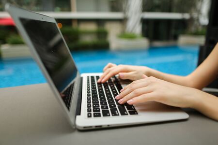 Close up portrait of woman hands pressing buttons on laptop at sunny day. Fingers typing on the computer keyboard. concept of business freelance working, new technologiesの写真素材