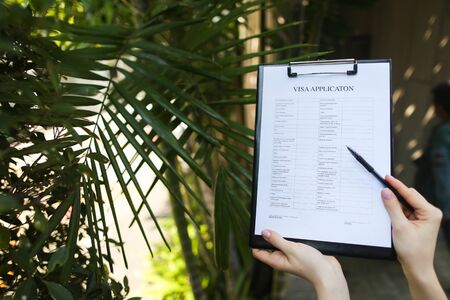 Beautiful hands of girl suggest signing an empty paper or contract on background of palms and sun. concept of working in warm countries, travel or remote work freelancing. Front used with Open Font Licenseの写真素材