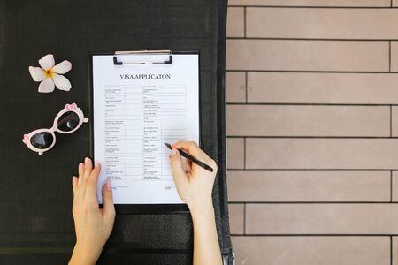 flat lay of woman hands fill application for business travel, sunlight portrait with sunglasses and tropical flower. concept of traveling journey for business meeting, international exchange. Front used with Open Font Licenseの写真素材