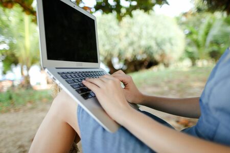 Female hands using laptop with sand in background, black screen. Concept of freelanctr, summer vacations and modern technology.の写真素材