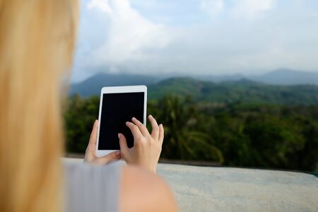 Female person using tablet in mountains background. Concept of nature and technology.の写真素材