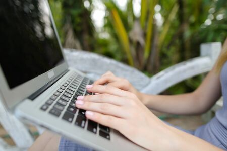 Female caucasian hands using laptop, palms in background. Concept of exotic summer vacations and modern technology.の写真素材