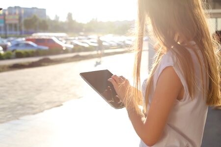 Female work, negotiating, solves problems, browsing touch looking tablet. Young beautiful business woman entrepreneur with long hair wearing suit standing near center technology sun.の写真素材