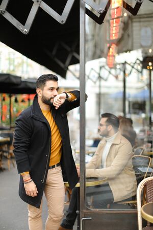 Young fashionable caucasian man standing at street cafe outdoors. Concept of life style and male fashion.の写真素材