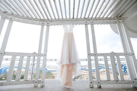 White bridal beautiful dress hanging on hanger outside. Concept of wedding morning and preparing,の写真素材