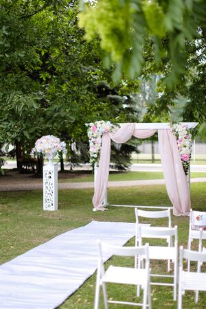 Beautiful decorated wedding arch and chairs in garden. Concept of marriage ceremony place and photo session in open air.の写真素材