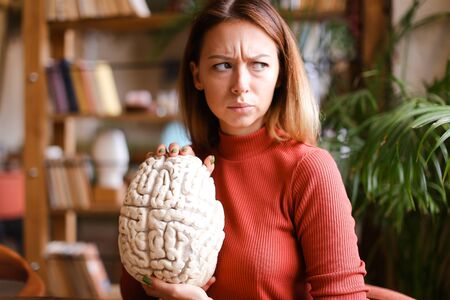 Strict female teacher holding human brain model in class room. Concept of anatomy lesson and medical...